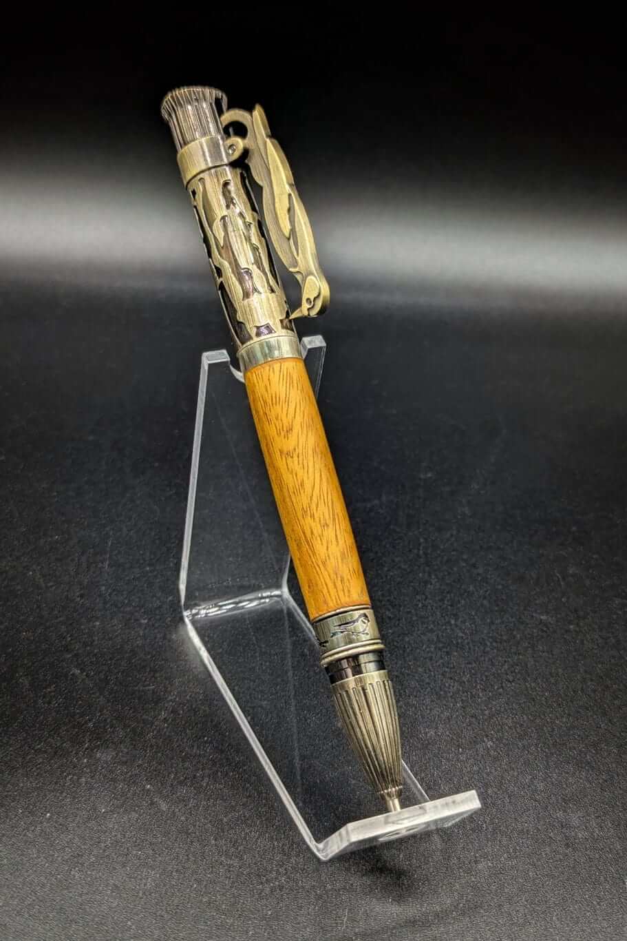 Stylo artisanal fait à la main en bois et résine acrylique colorée, posé sur un support avec fond noir