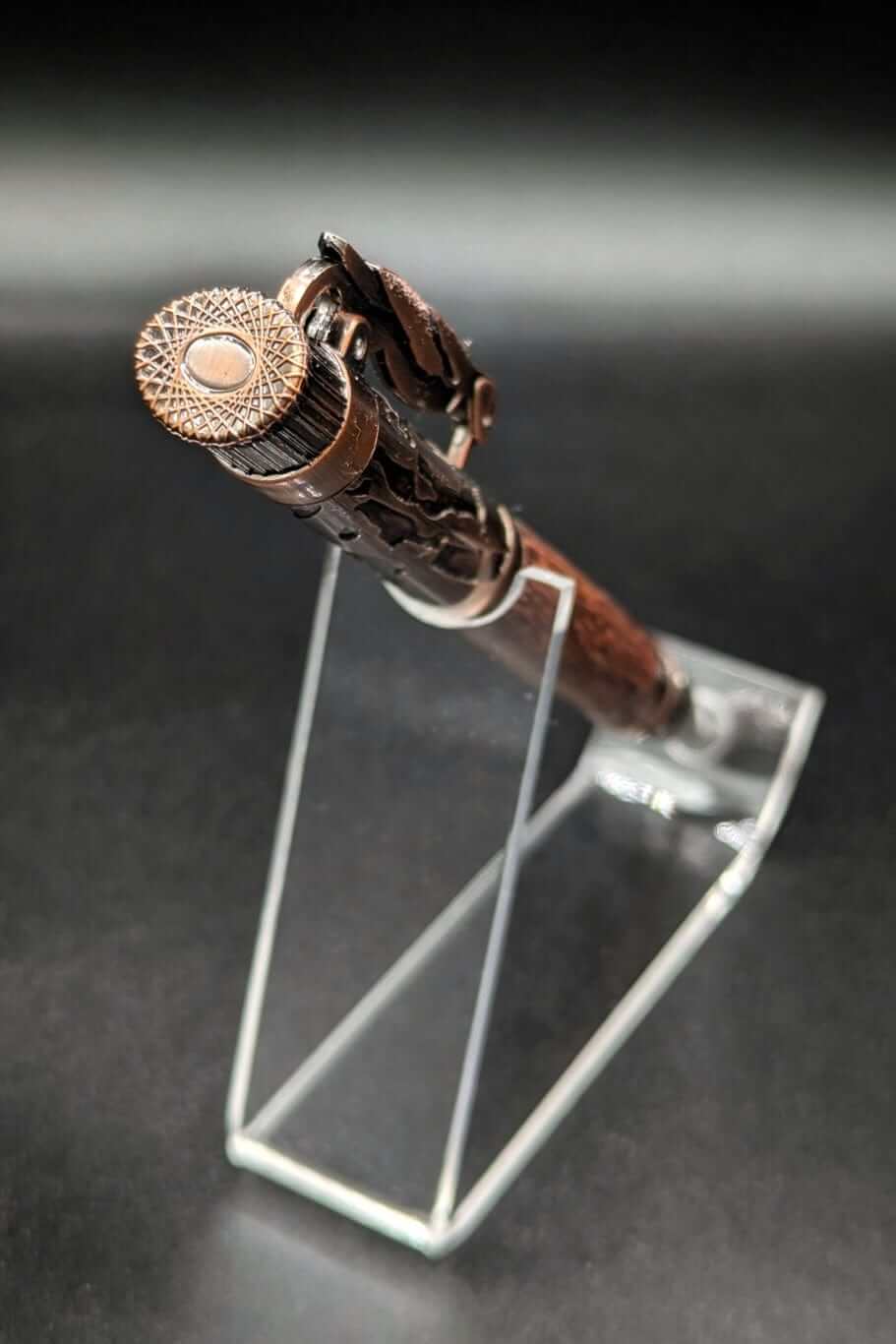 Stylo artisanal fait à la main en bois et résine acrylique colorée, posé sur un support avec fond noir