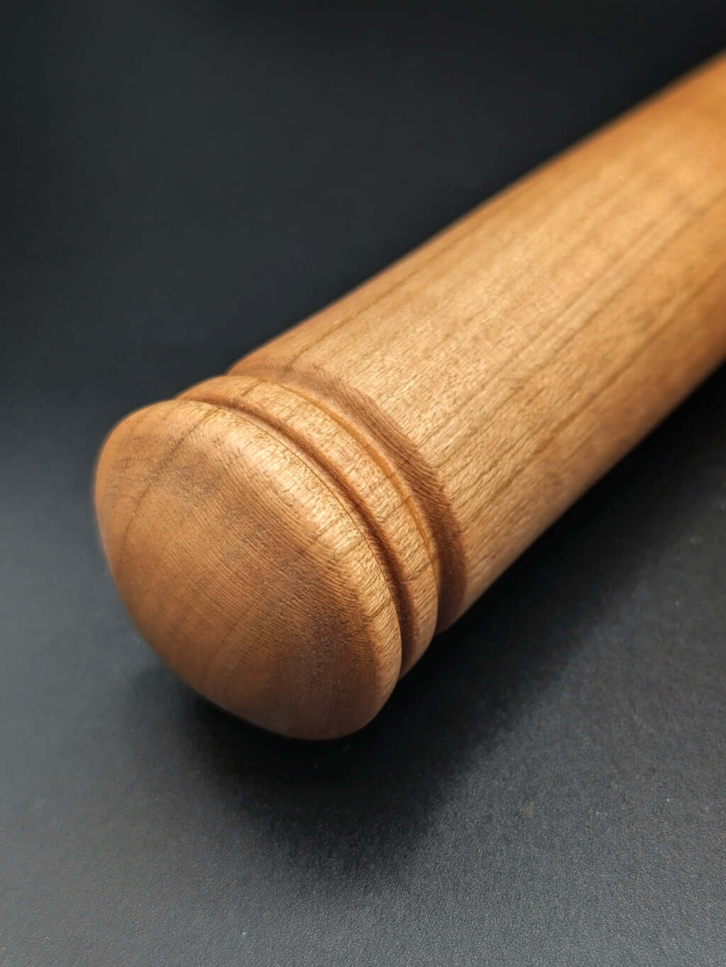 Stylo artisanal fait à la main en bois et résine acrylique colorée, posé sur un support avec fond noir