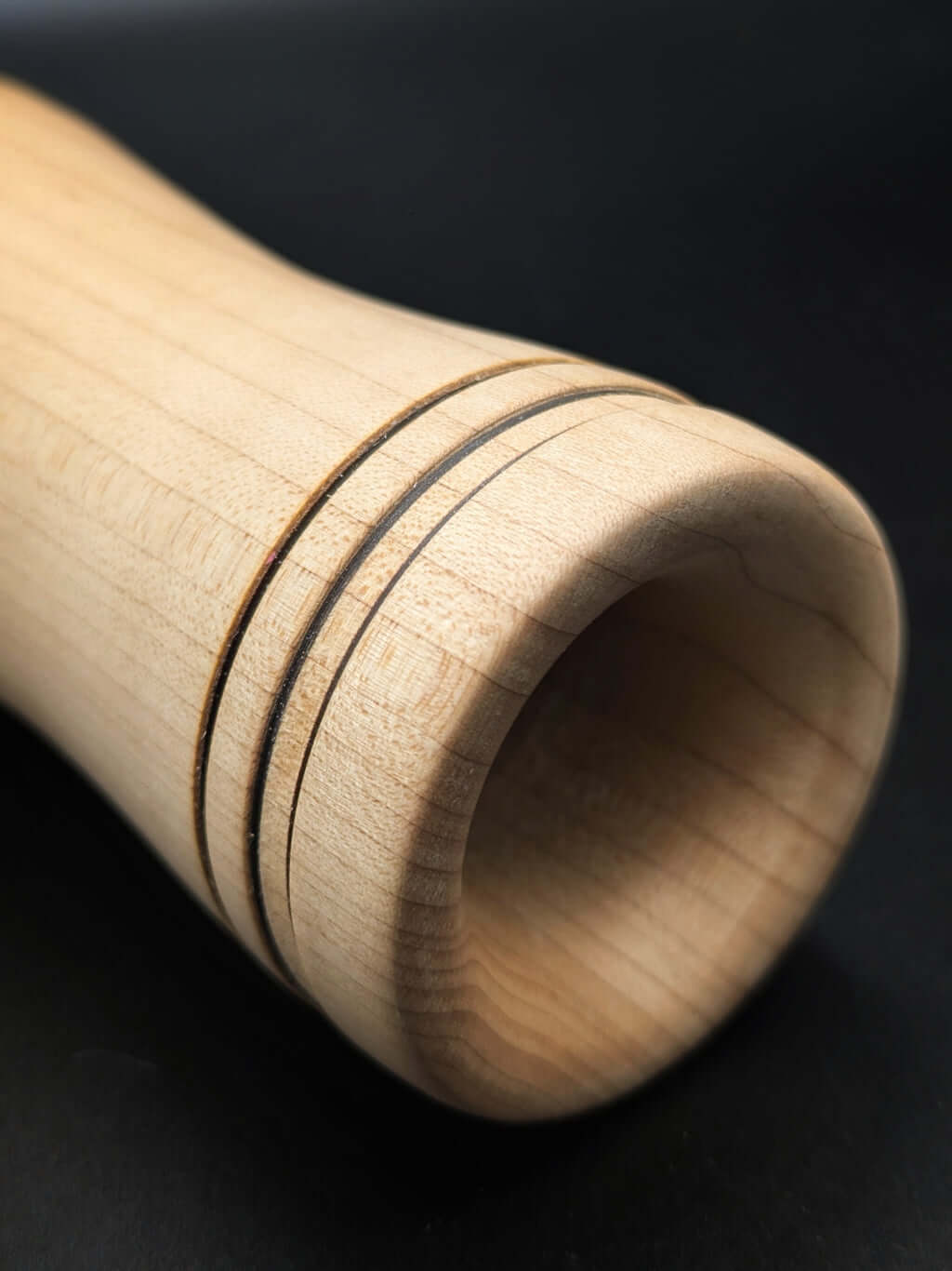 Stylo artisanal fait à la main en bois et résine acrylique colorée, posé sur un support avec fond noir