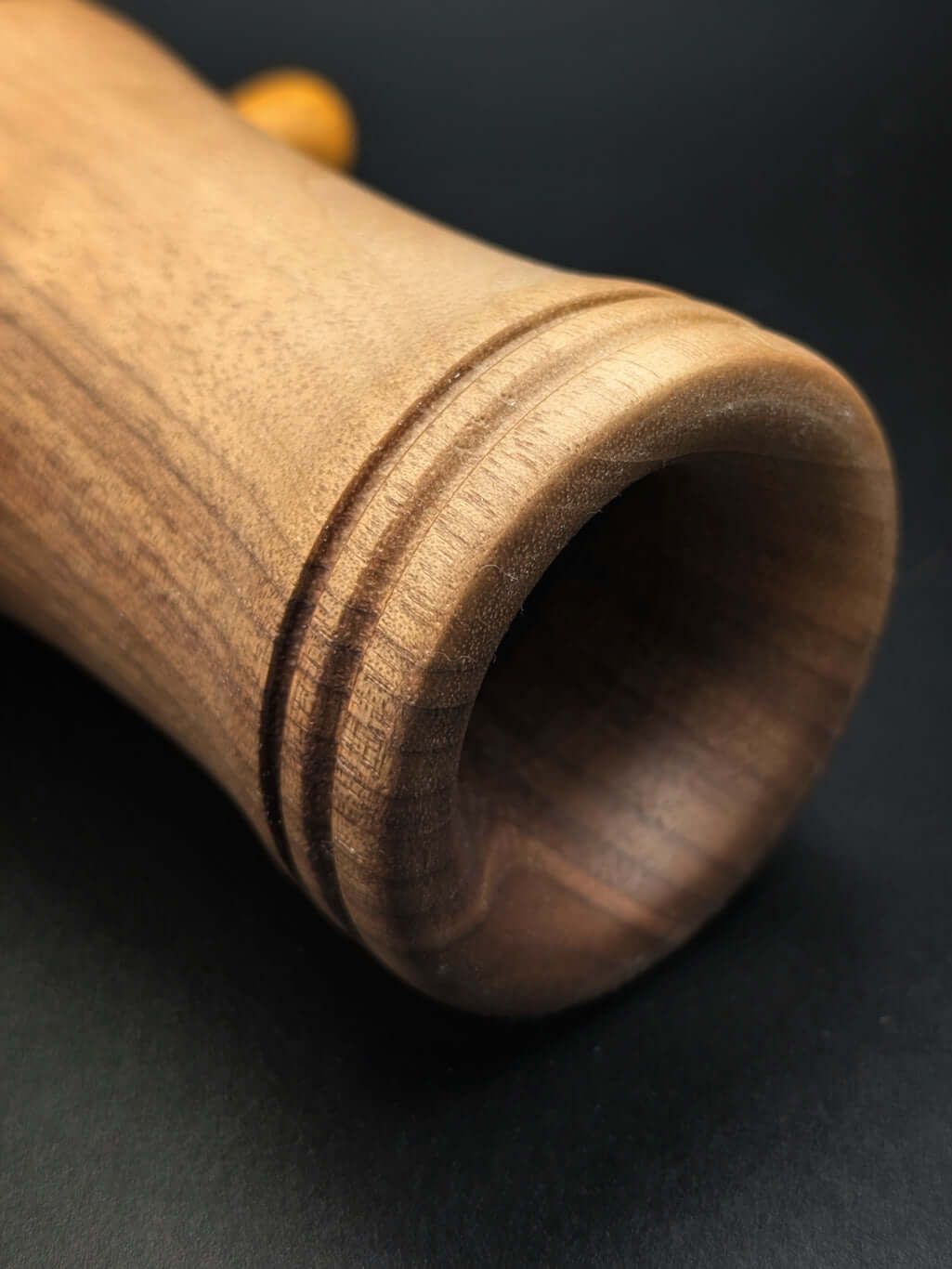 Stylo artisanal fait à la main en bois et résine acrylique colorée, posé sur un support avec fond noir