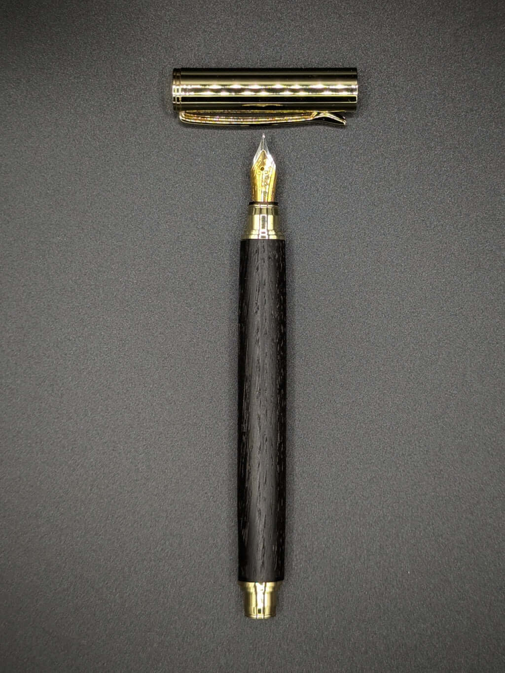 Stylo artisanal fait à la main en bois et résine acrylique colorée, posé sur un support avec fond noir