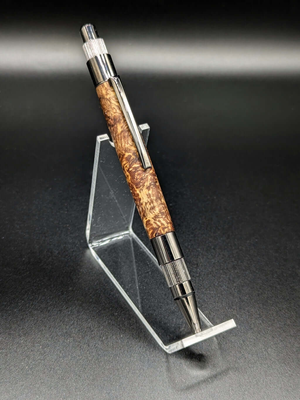 Stylo artisanal fait à la main en bois et résine acrylique colorée, posé sur un support avec fond noir