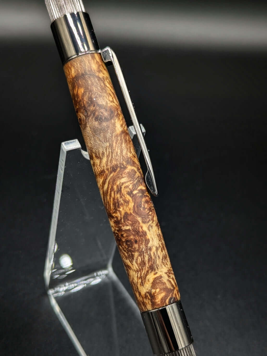 Stylo artisanal fait à la main en bois et résine acrylique colorée, posé sur un support avec fond noir