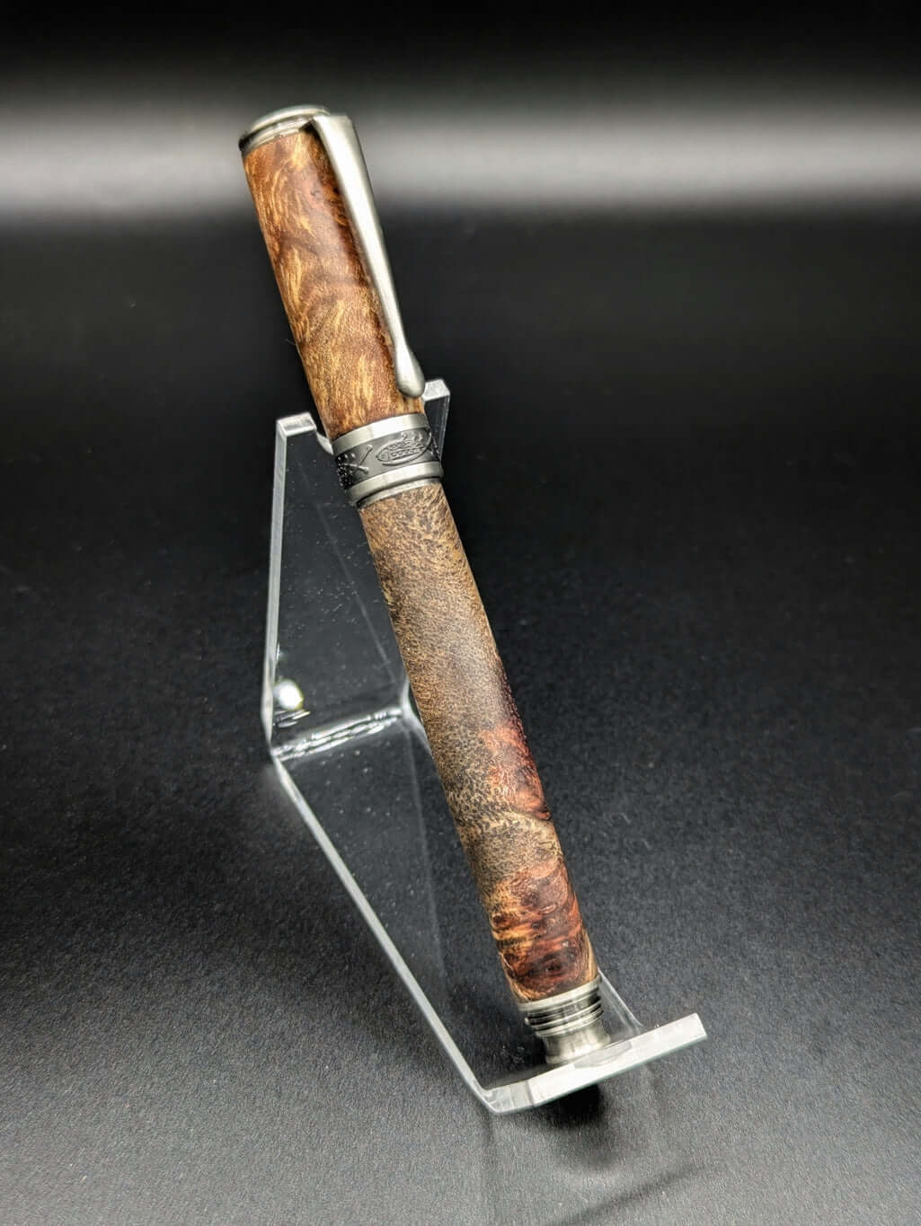 Stylo artisanal fait à la main en bois et résine acrylique colorée, posé sur un support avec fond noir