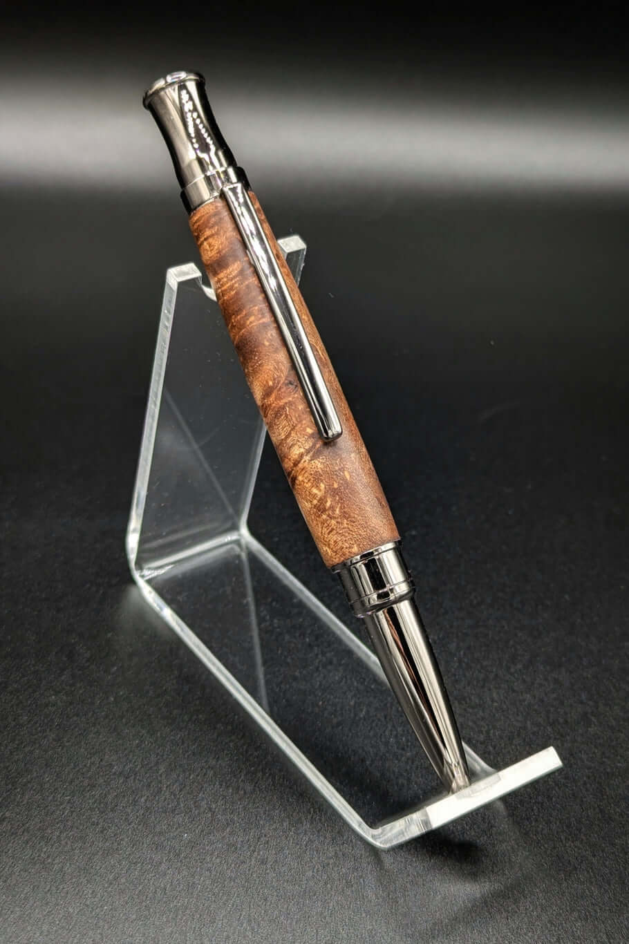 Stylo artisanal fait à la main en bois et résine acrylique colorée, posé sur un support avec fond noir