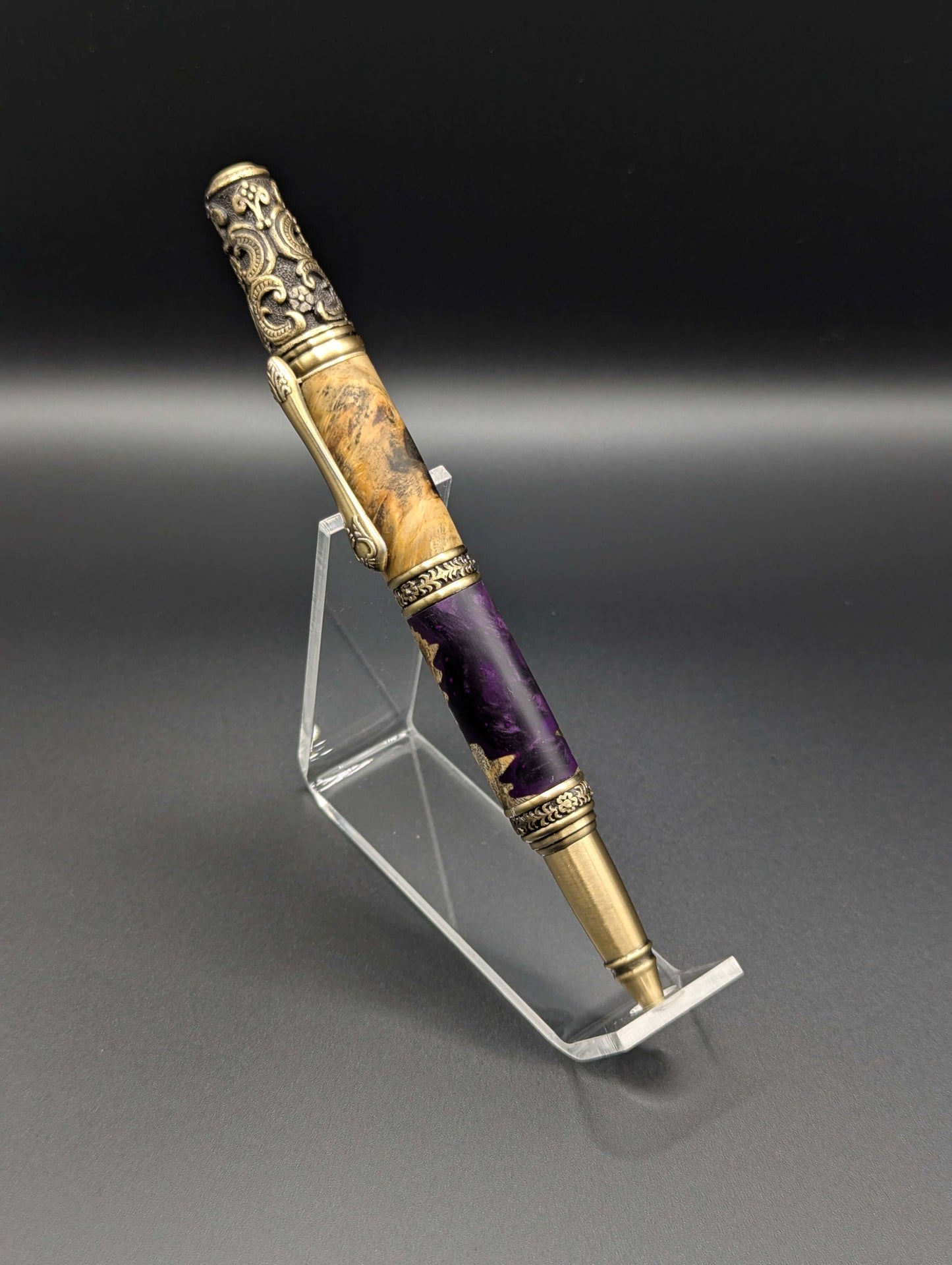 Stylo artisanal fait à la main en bois et résine acrylique colorée, posé sur un support avec fond noir