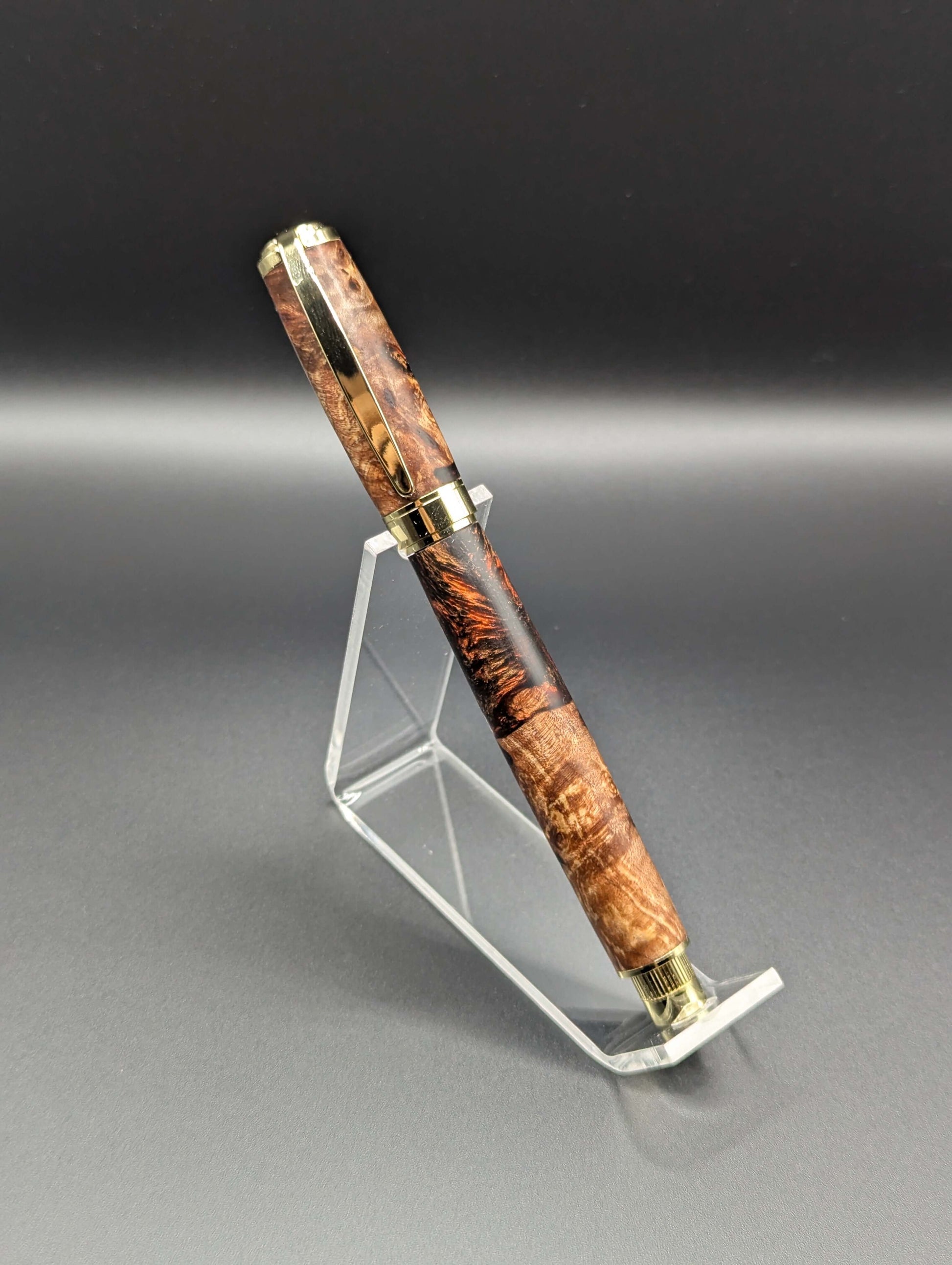 Stylo artisanal fait à la main en bois et résine acrylique colorée, posé sur un support avec fond noir