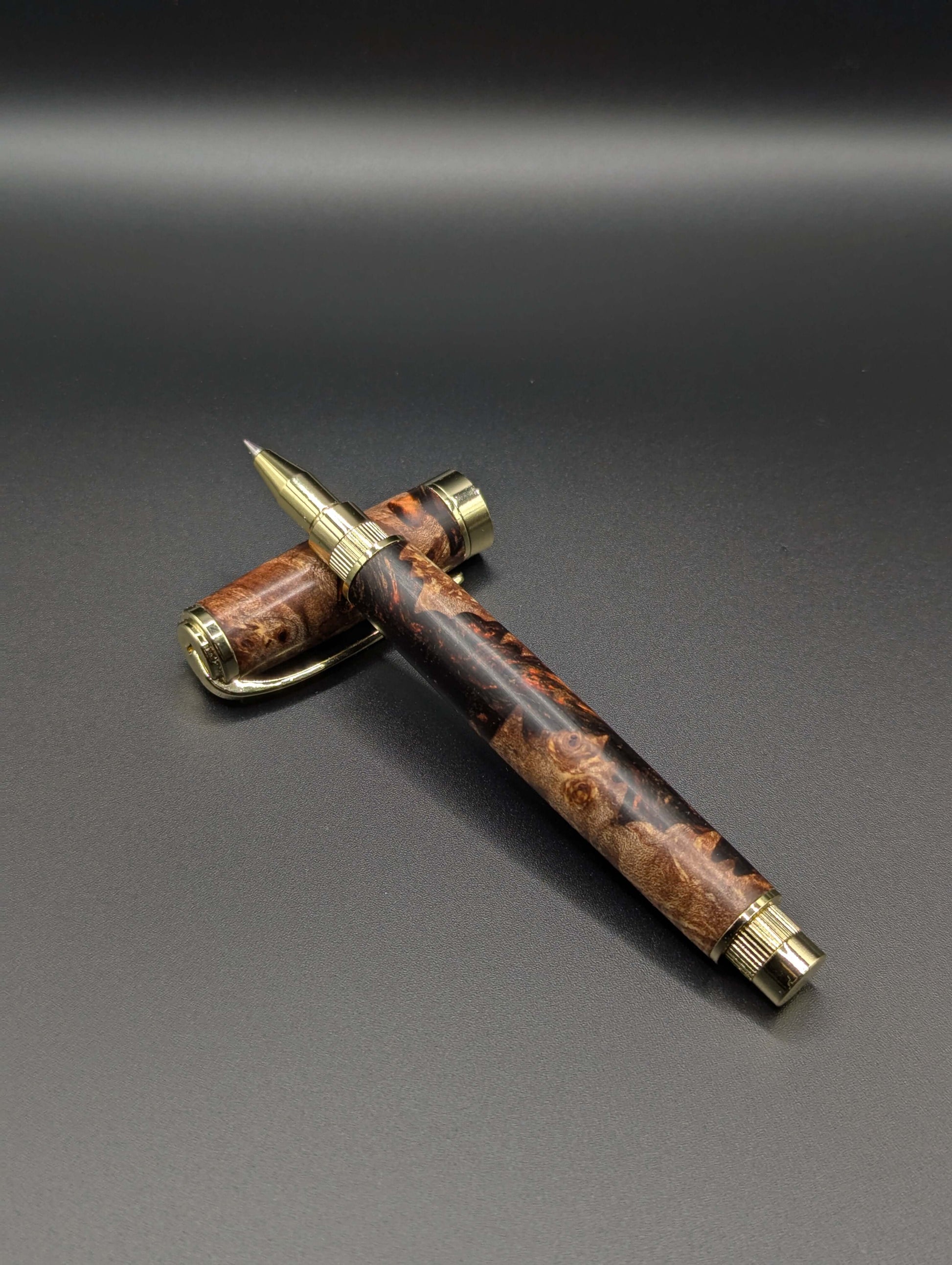 Stylo artisanal fait à la main en bois et résine acrylique colorée, posé sur un support avec fond noir